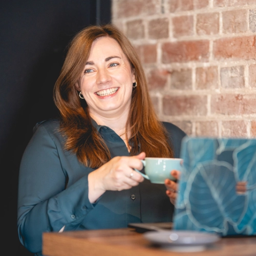 Annie Browne drinking coffee working at laptop